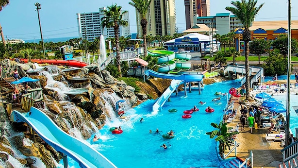 A water park with multiple slides and water features, surrounded by palm trees and buildings. - Sea Sprite (Destin)