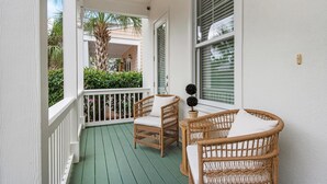A covered porch with wicker furniture and a potted plant. - Dock Holiday (Panama City Beach)