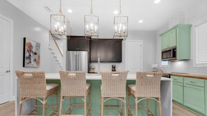A modern kitchen with a central island, dark cabinets, and green accents. - Dock Holiday (Panama City Beach)