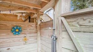 Eine Holzhütte mit Dusche, Holzwänden und einer Wanddekoration mit Blumen.