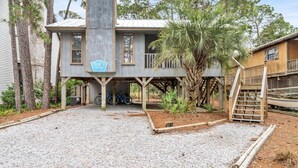 Ein zweigeschossiges Haus mit überdachter Veranda und einem Schotterweg.