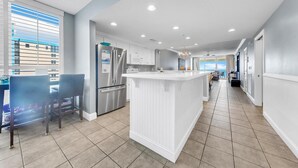 A modern kitchen with a central island, stainless steel appliances, and a dining area with chairs.