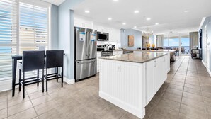 A modern kitchen with white cabinetry, stainless steel appliances, and a large island.