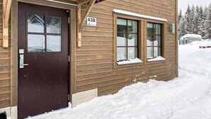 Une cabane en bois avec une porte marron et deux fenêtres, portant l’inscription « 43B ».