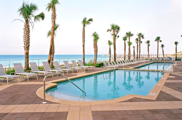 A pool area with lounge chairs and palm trees, overlooking the sea. - Sterling Reef 401 (Panama City Beach)