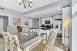 A modern kitchen with white cabinets, a central island, and stainless steel appliances. - Sterling Reef 401 (Panama City Beach)