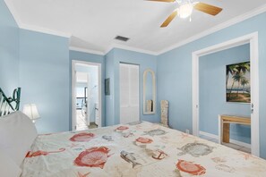 Ein Schlafzimmer mit Bett, Deckenventilator, Tür, Spiegel und einem Gemälde an der Wand.