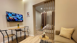 Una sala moderna con una televisión de pantalla plana, un comedor con mesa y sillas, un sofá y una alfombra decorativa.