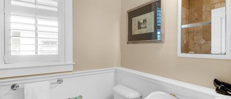 A bathroom with a toilet, sink, and window with blinds.