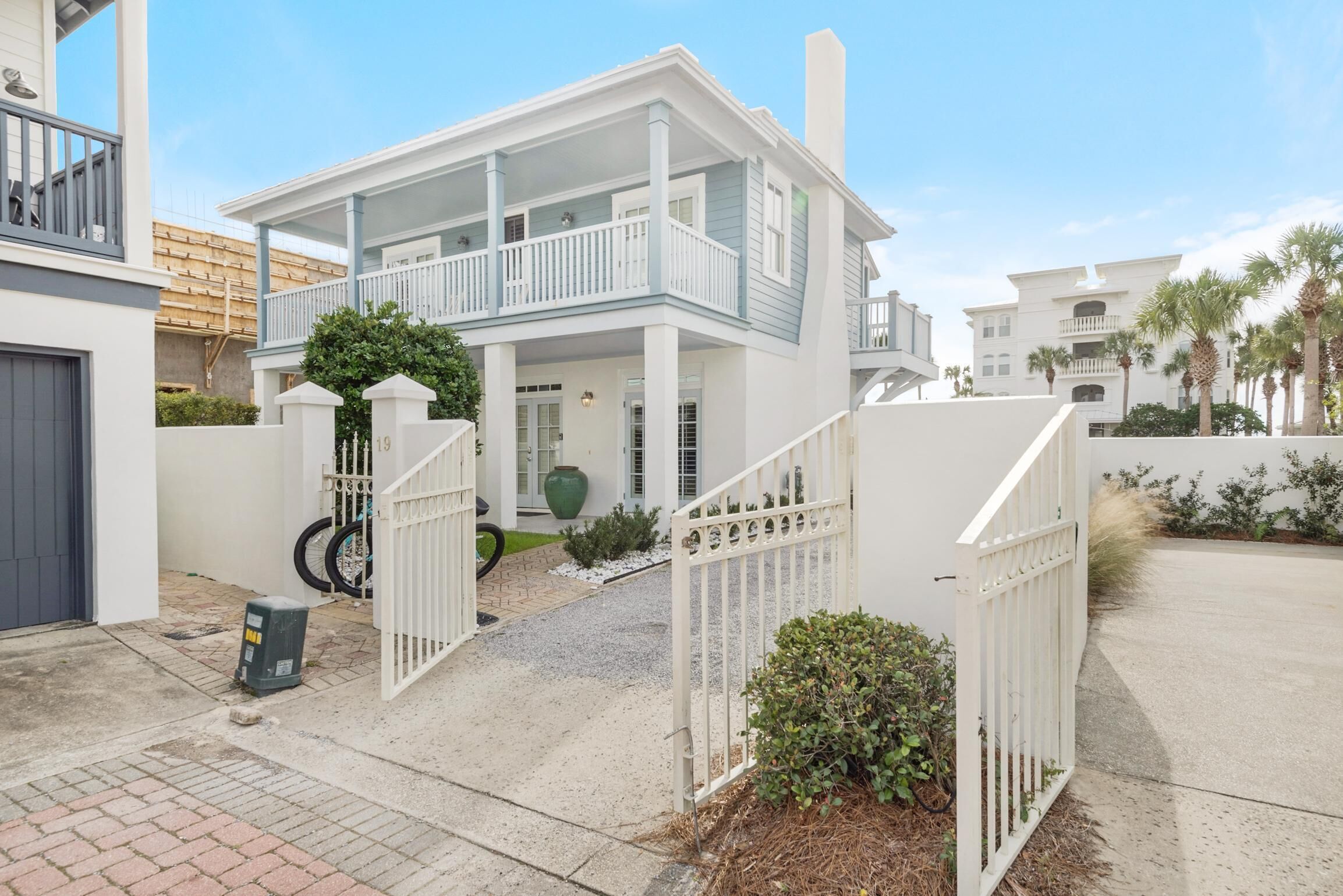 A two-story house with a balcony, a gated driveway, and a small garden area.