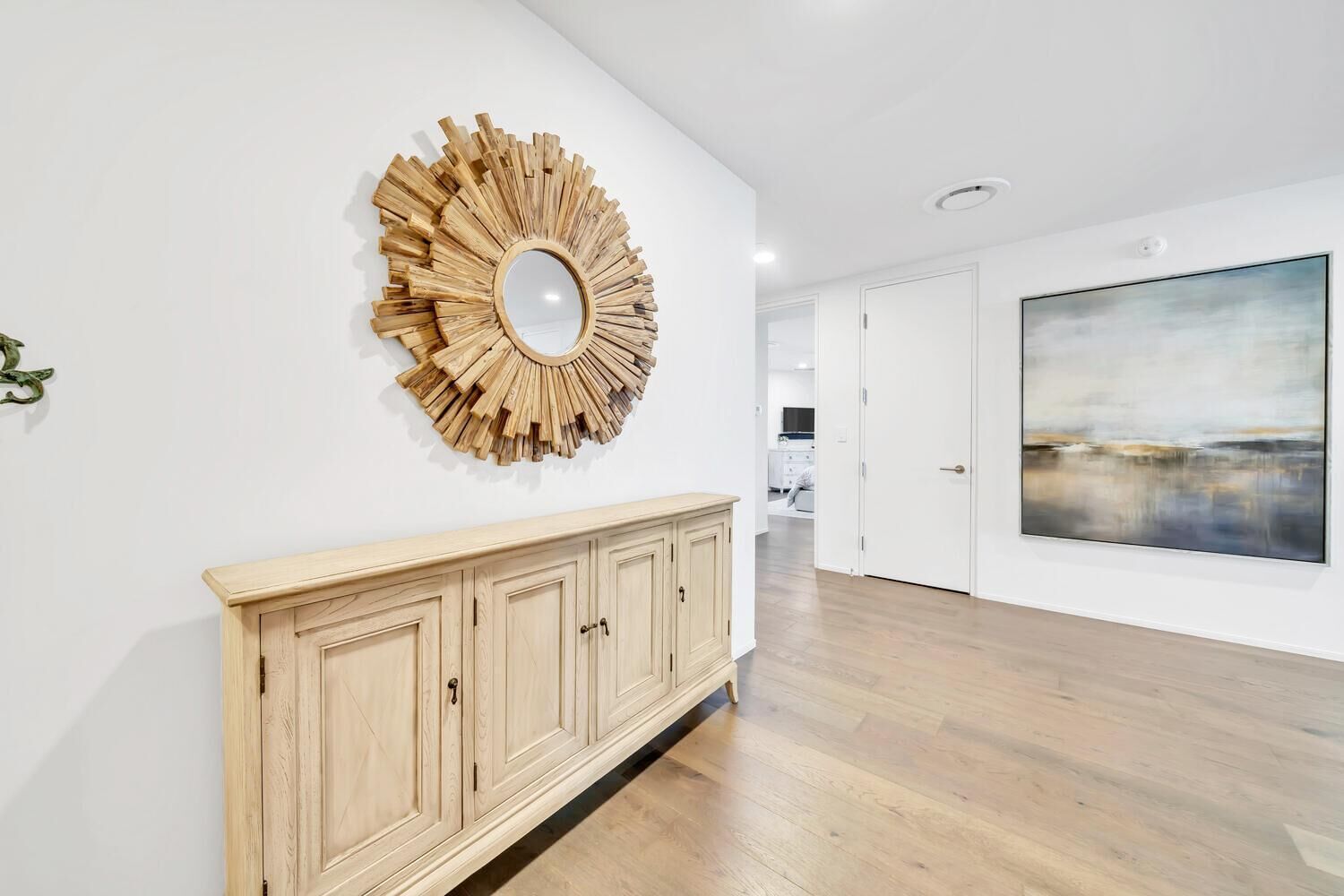 A spacious room with a wooden cabinet, a large mirror, and a painting on the wall.