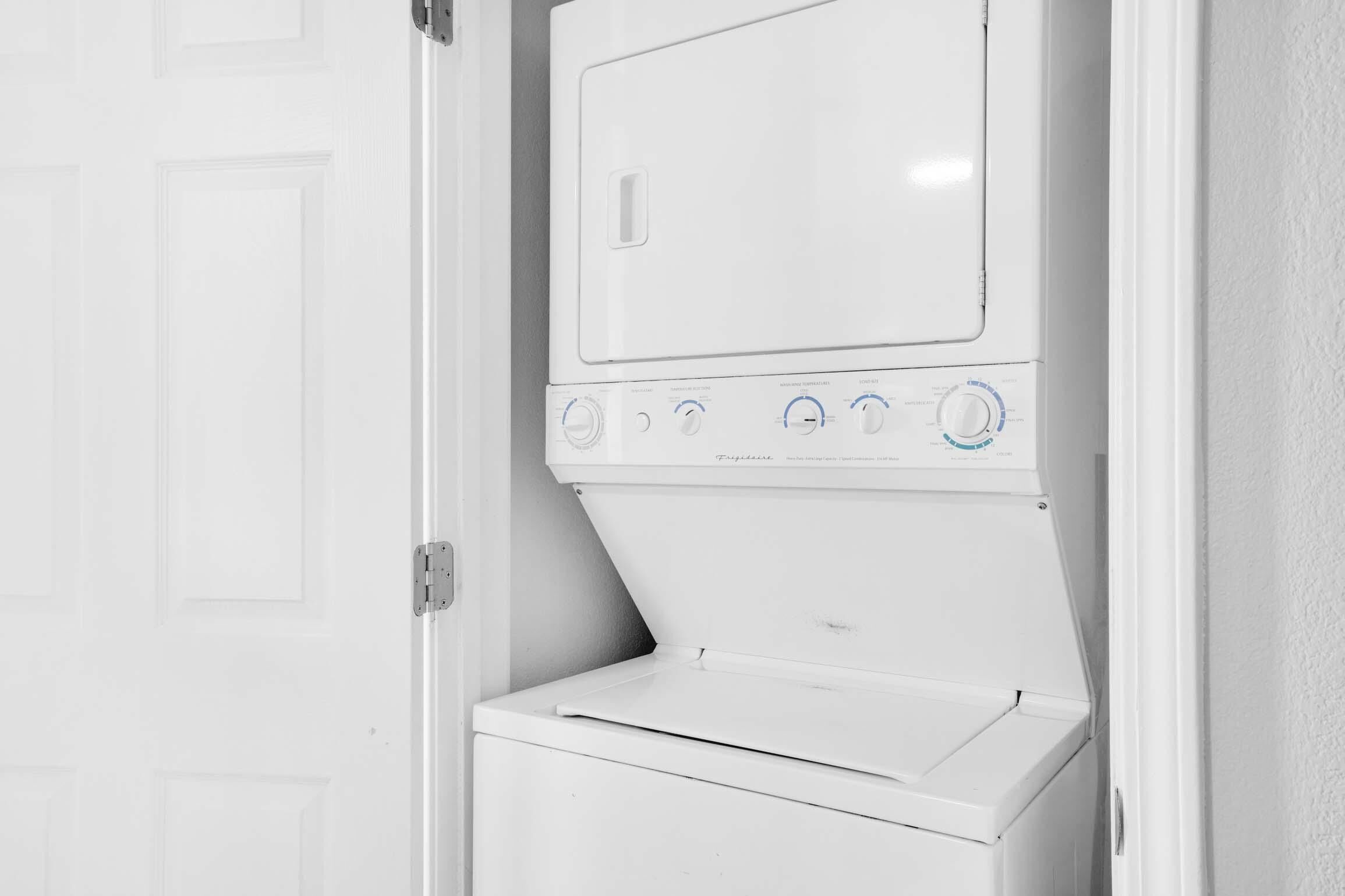 Una lavadora y secadora apilables blancas con perillas de control y una puerta.