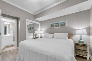 Une chambre à coucher avec un grand lit, des lampes de chevet, un miroir et un tableau encadré au mur.
