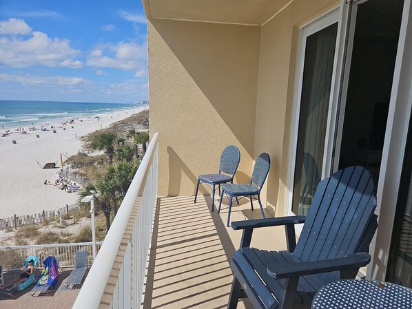 Un balcon avec deux chaises, une vue sur la plage et une clôture.