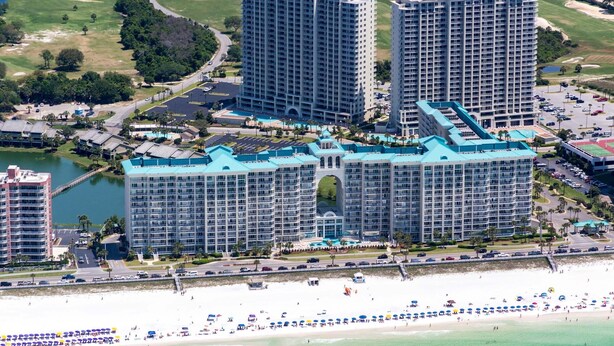 Un grand complexe hôtelier comprenant plusieurs immeubles de grande hauteur, une plage et un terrain de golf bien entretenu.