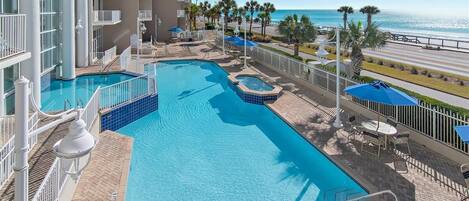 Un área de piscina con vista despejada al océano, un jacuzzi y mobiliario exterior.