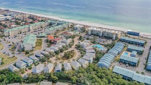 An aerial view of a coastal resort with multiple buildings, a beach, and a swimming pool. - A Piece of Heaven (Miramar Beach)