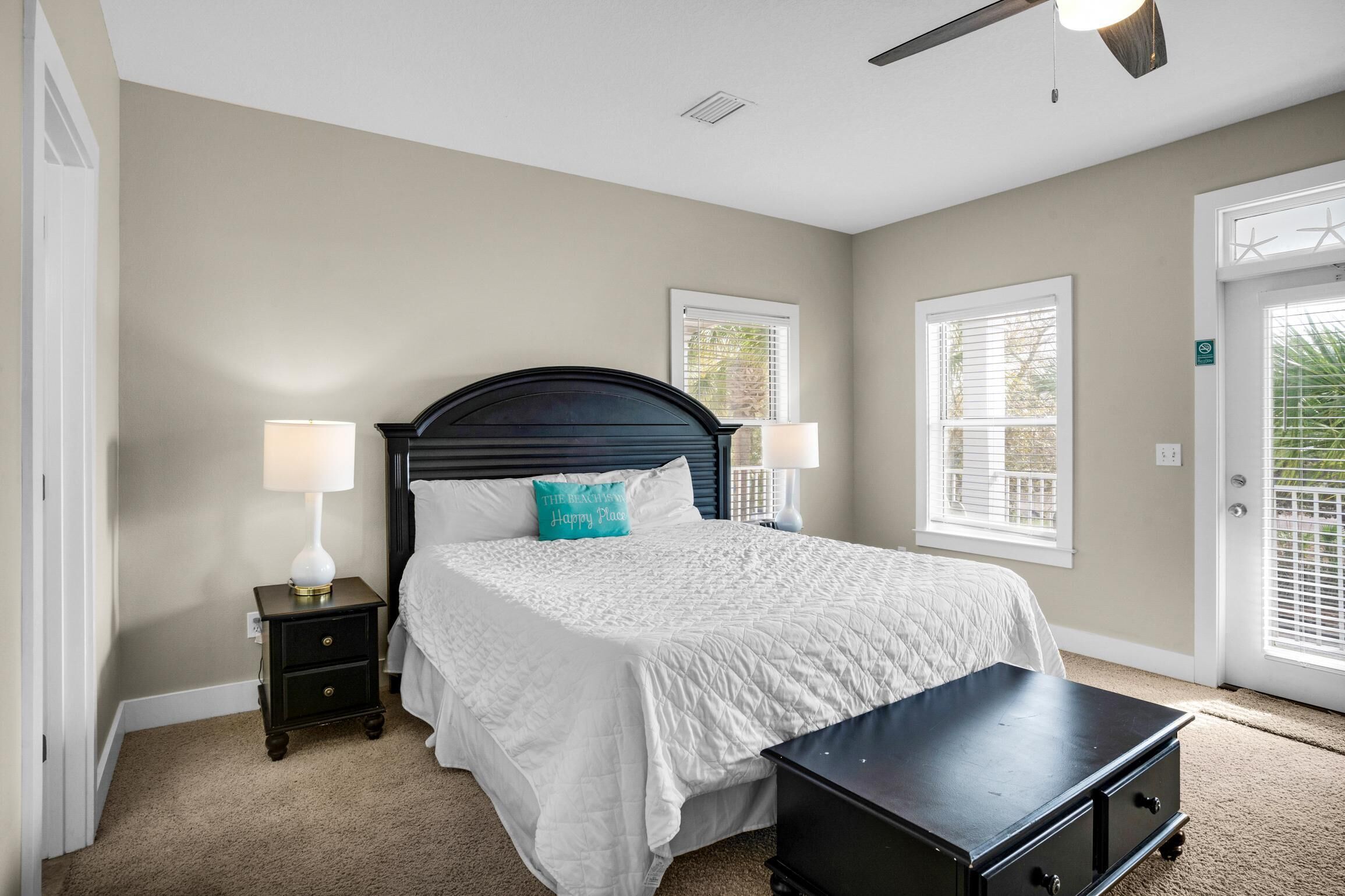 A bedroom with a bed, nightstands, a dresser, and a ceiling fan.