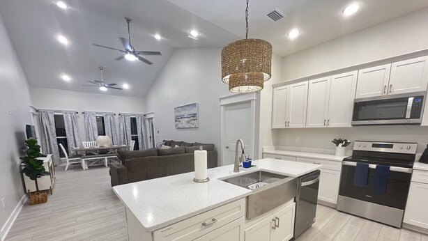 A modern kitchen with white cabinetry, a stainless steel oven, and a large island with a sink.