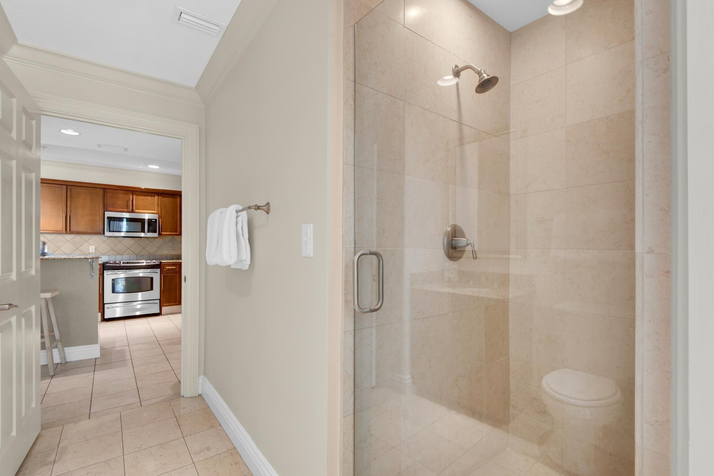 A modern bathroom with a glass-enclosed shower, a toilet, and a sink.