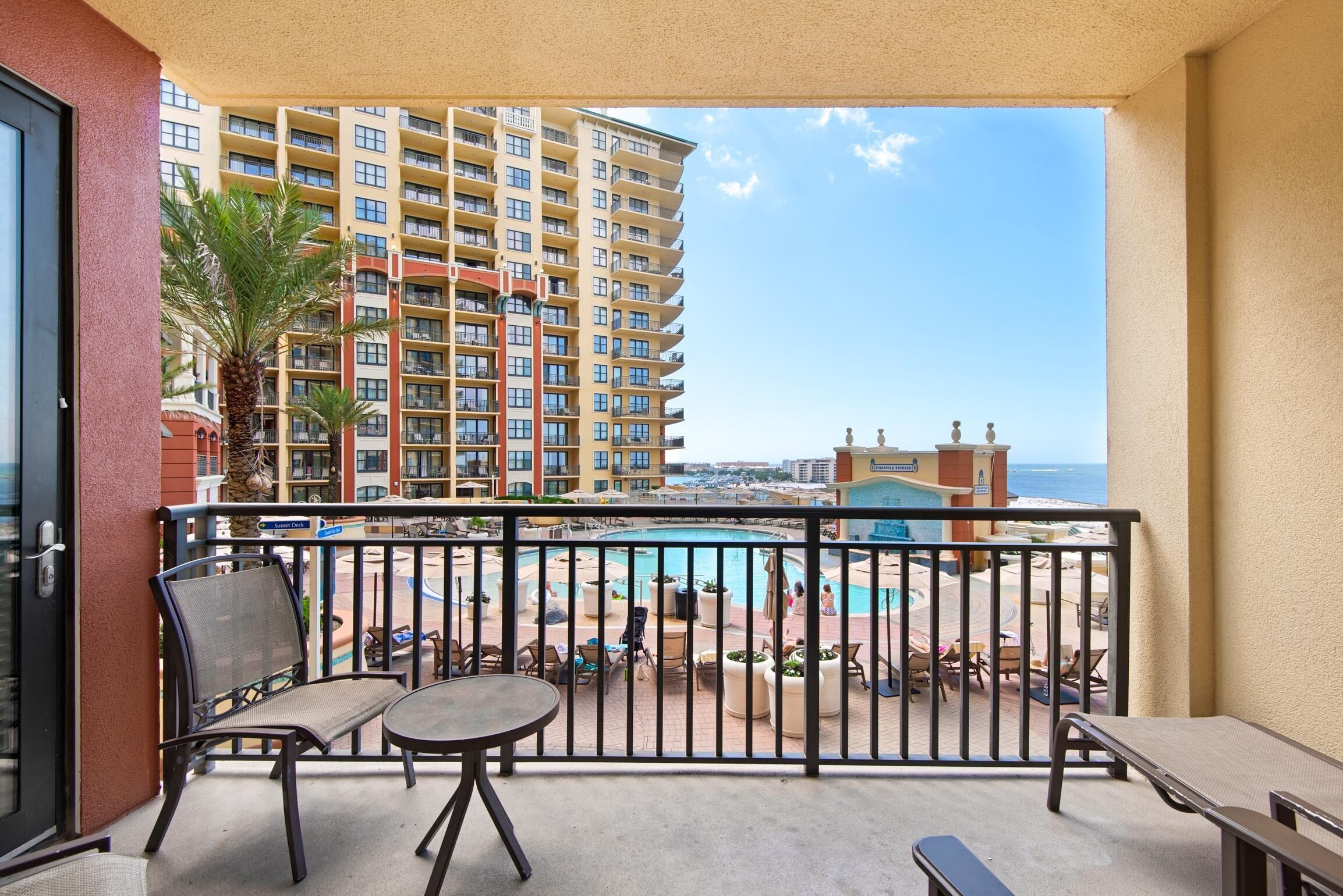 A balcony with a view of a pool and a high-rise building in the background.
