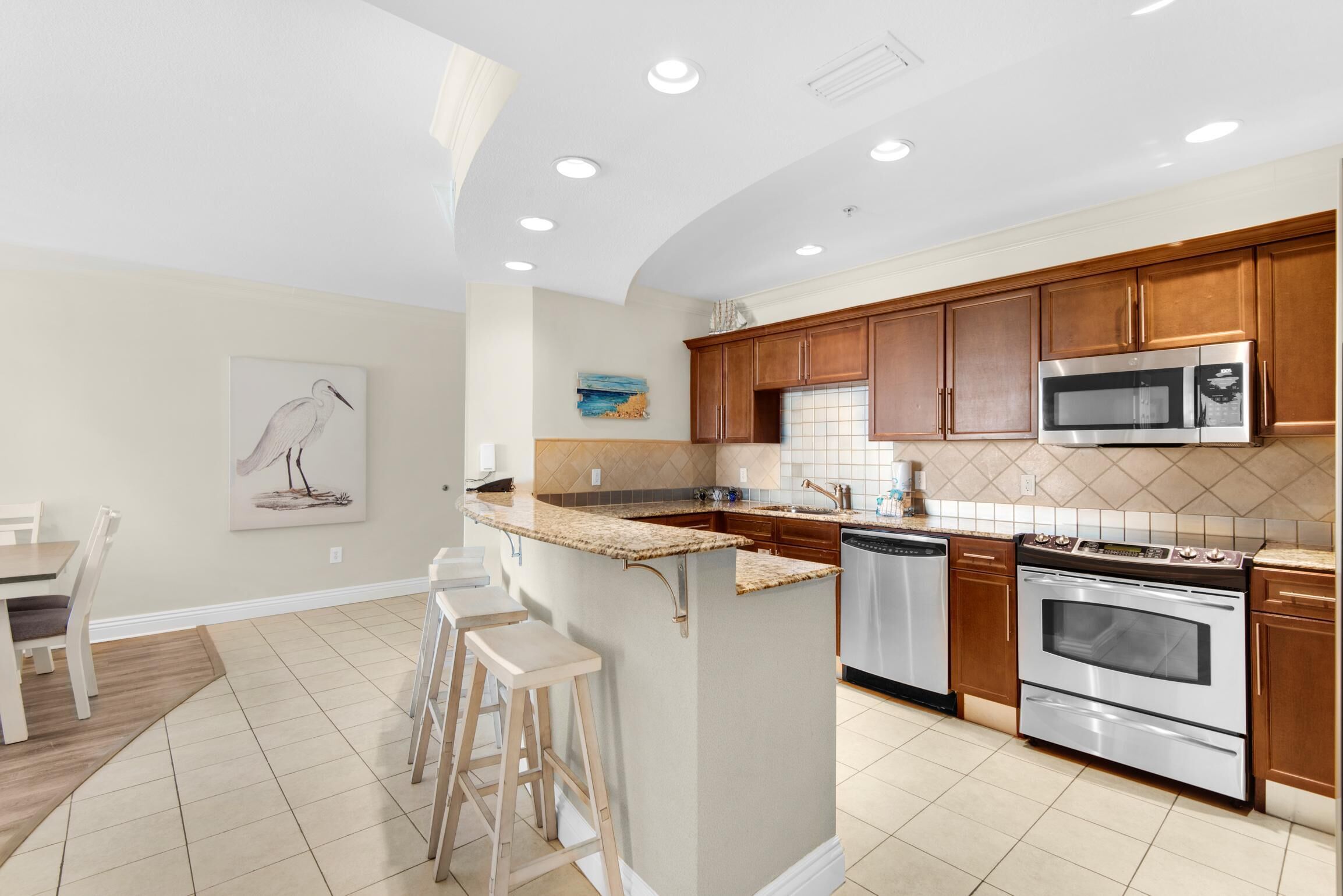 A modern kitchen with wooden cabinets, stainless steel appliances, and a central island with stools.