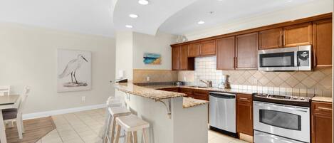 A modern kitchen with wooden cabinets, stainless steel appliances, and a central island with stools.
