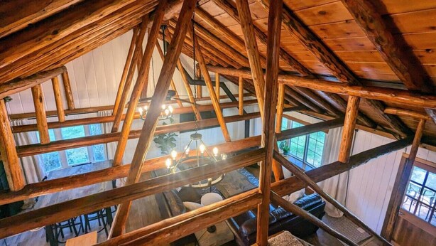 Een kamer met hoge plafonds, zichtbare houten balken en een kroonluchter.