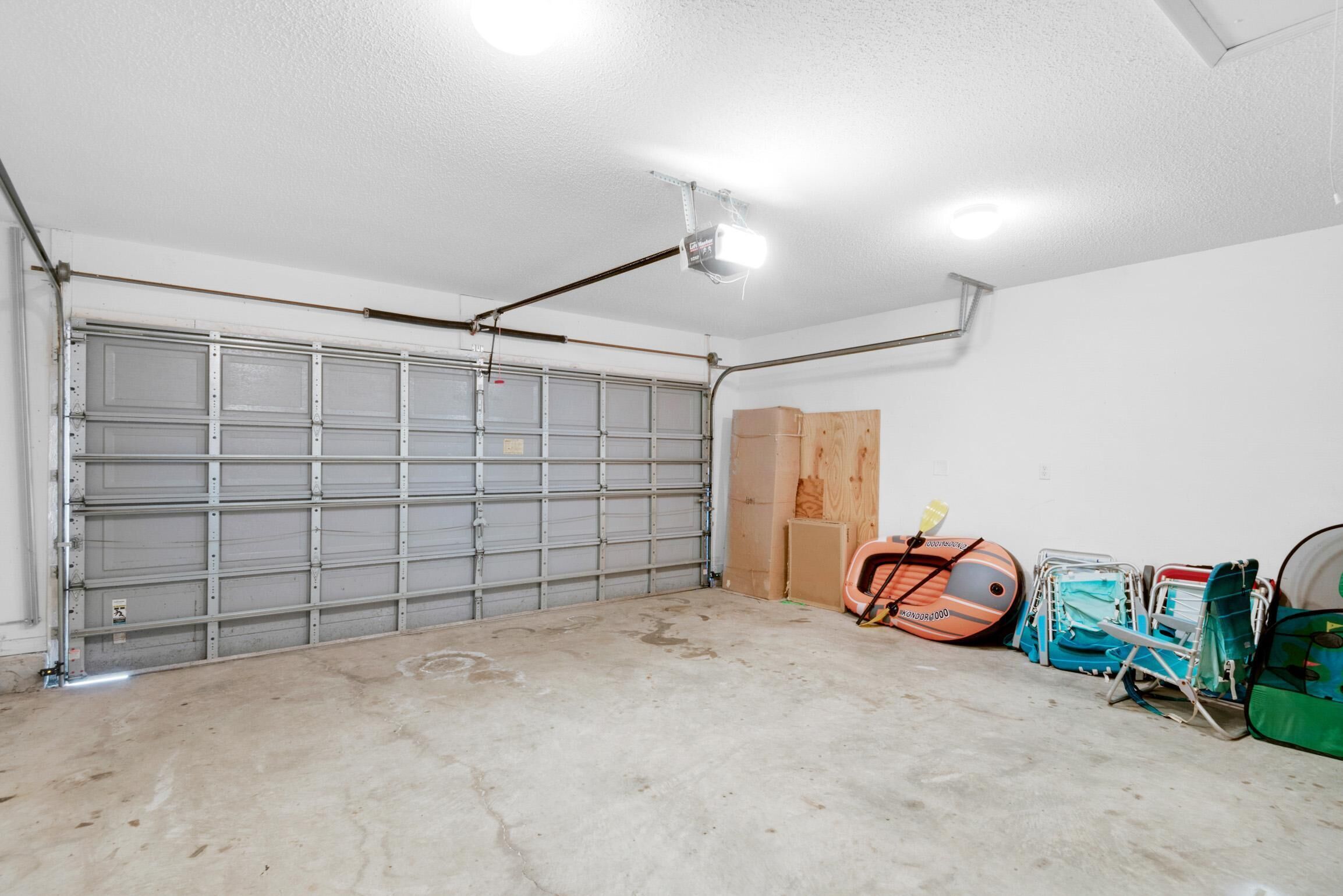 Eine Garage mit einer geschlossenen Metalttür, einem an der Decke befestigten Projektor und verschiedenen Gegenständen, darunter ein Koffer und Kartons.