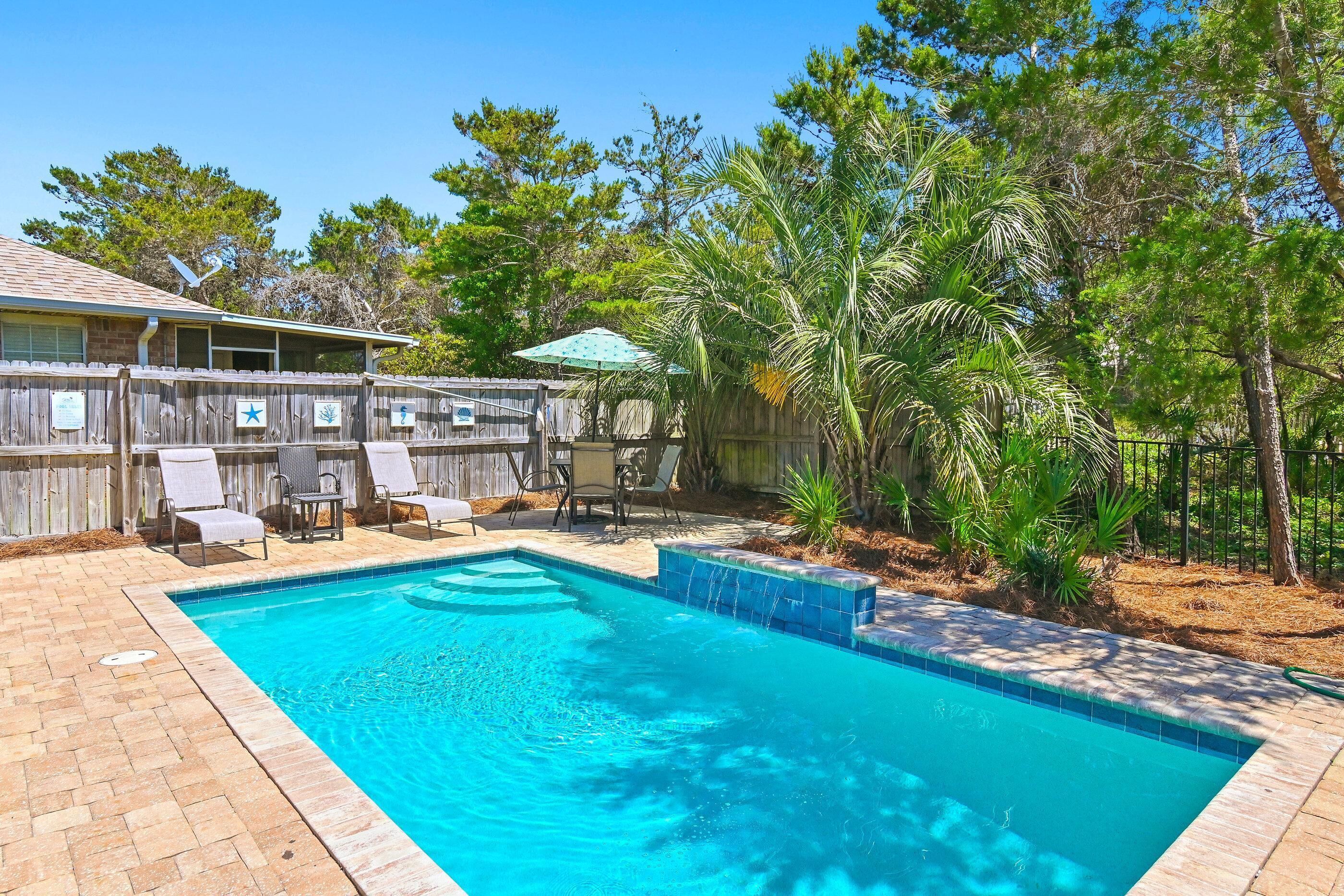 Un jardin avec une piscine, du mobilier de jardin et une clôture en bois.