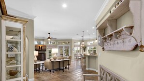 A spacious living area with a high ceiling, a fireplace, and a dining area with a chandelier.