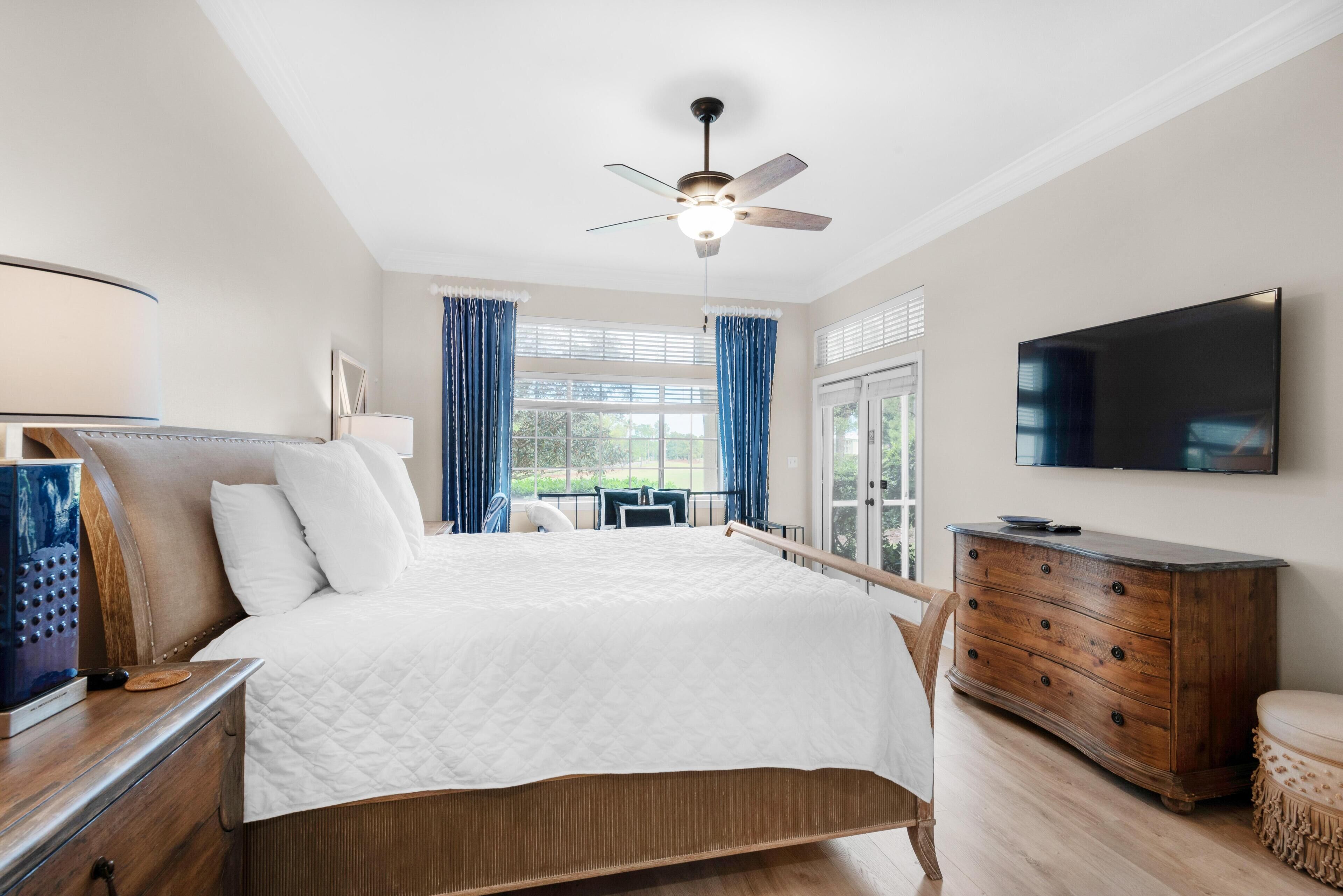A bedroom with a bed, a dresser, a television, and a ceiling fan.