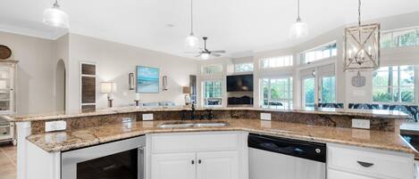 A spacious kitchen with granite countertops, white cabinetry, and a dishwasher.