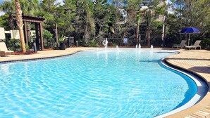 Ein Schwimmbecken mit Backsteinbordstein, umgeben von Bäumen und einer Pergola.