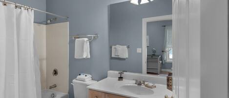 A bathroom with a bathtub, toilet, sink, and vanity.