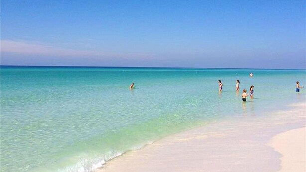 Ein Strand mit klarem türkisfarbenem Wasser und einem Sandufer.