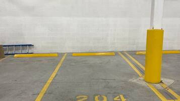 Un estacionamiento con paredes de concreto, un pilar amarillo y un espacio marcado con el número 204.