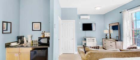 A bedroom with a bed, a dresser, a TV, and a window with curtains.