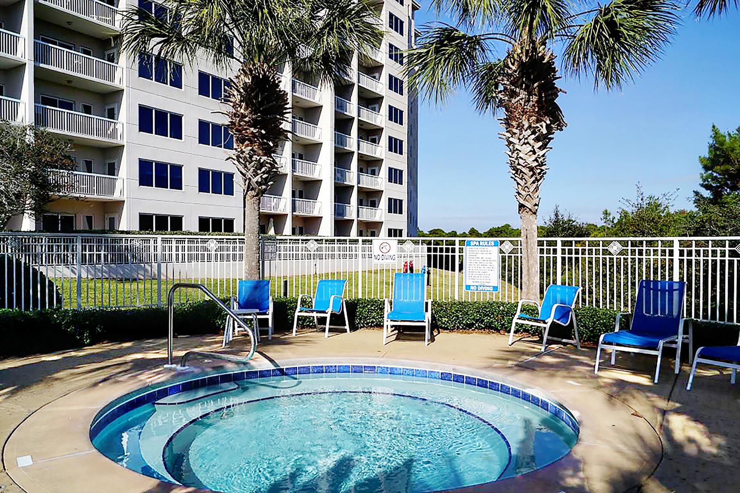 A swimming pool with blue chairs and a white fence.