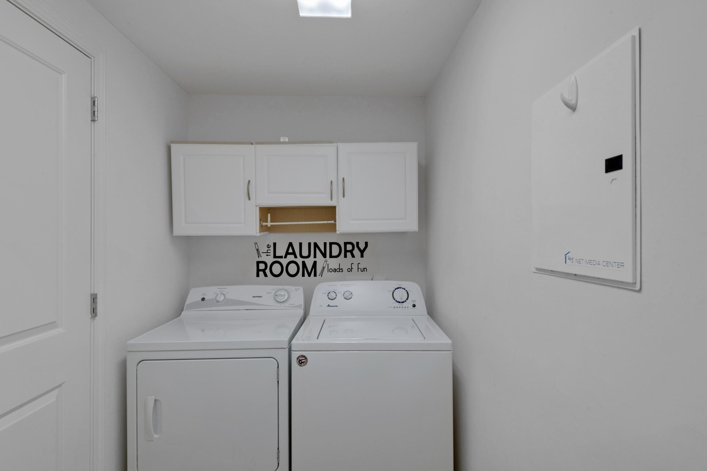 A laundry room with two washing machines, a drying rack, and a wall-mounted drying unit.