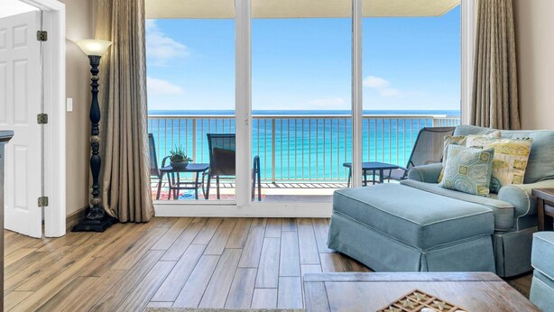 A room with a view of the ocean, a sofa, a table, and a lamp. - Majestic Beach Towers 2-901 (Panama City Beach)