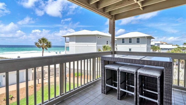 Ein überdachter Balkon mit Blick auf das Meer und Strandhäuser.