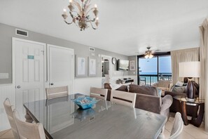 Ein modernes Wohnzimmer mit Essbereich, einem Chandelier und Blick auf den Ozean.