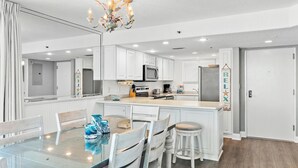 Uma cozinha moderna com armários brancos, uma ilha central e um lustre.