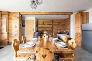 A wooden dining area with a long table, chairs, and a chandelier.