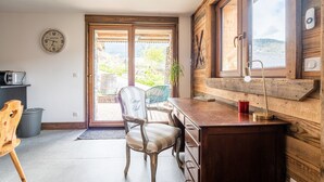 A wooden-framed room with a desk, chair, and a view through a glass door.