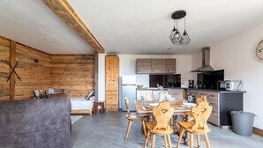 A modern kitchen with wooden cabinets, a dining area with a table and chairs, and a grey sofa.