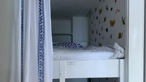A bunk bed room with a curtain, patterned wall, and butterfly wallpaper.