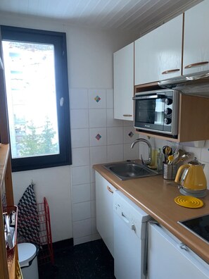 Pieni, käytännöllinen keittiö, jossa on mikroaaltouuni, pesuallas ja vedenkeitin.
