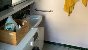 A bathroom with a sink, mirror, towel rack, and a washing machine.